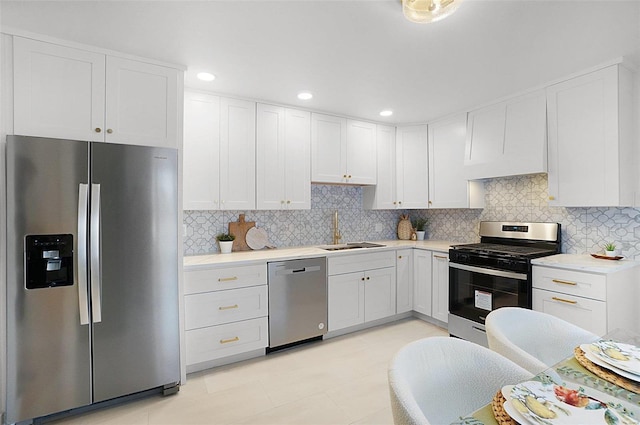 kitchen featuring stainless steel appliances, sink, white cabinetry, light tile patterned floors, and tasteful backsplash