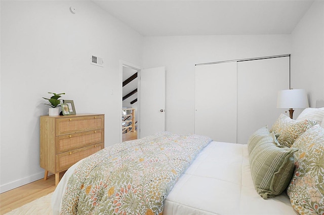 bedroom featuring wood-type flooring, a closet, and vaulted ceiling