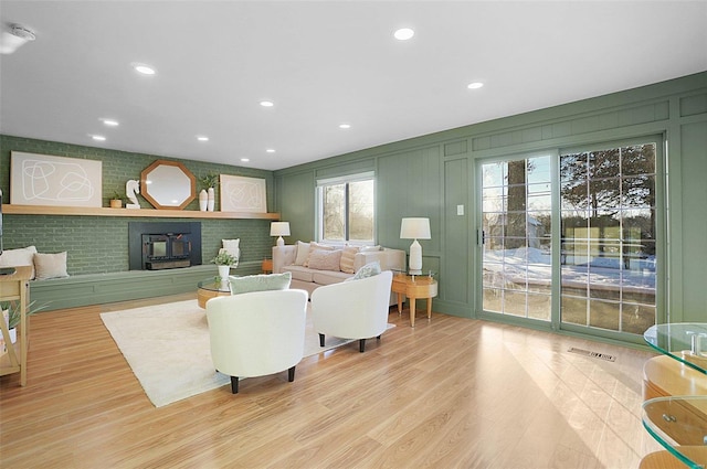 living room featuring a healthy amount of sunlight, light hardwood / wood-style flooring, and a wood stove