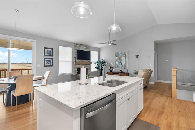 kitchen featuring a sink, a stone fireplace, white cabinets, stainless steel dishwasher, and open floor plan