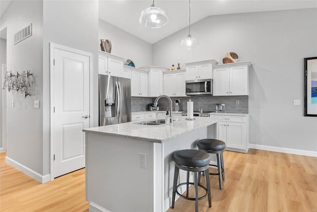 kitchen with light wood-style flooring, white cabinetry, stainless steel appliances, and a sink