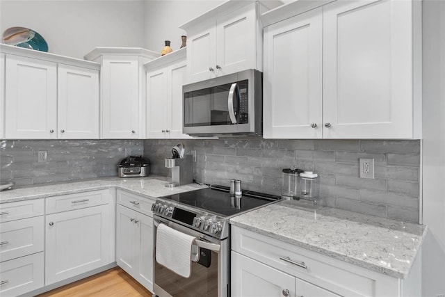 kitchen featuring tasteful backsplash, appliances with stainless steel finishes, and white cabinetry