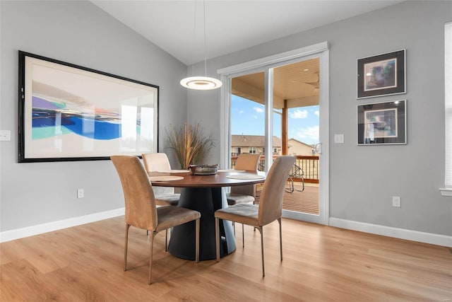 dining area with baseboards, lofted ceiling, and light wood-style flooring