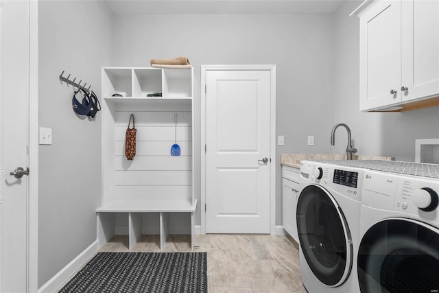 clothes washing area featuring washer and dryer, cabinet space, and baseboards