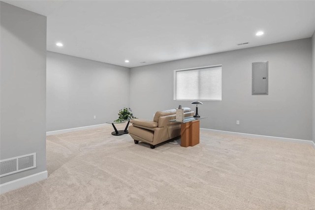 sitting room with electric panel, visible vents, baseboards, and light colored carpet