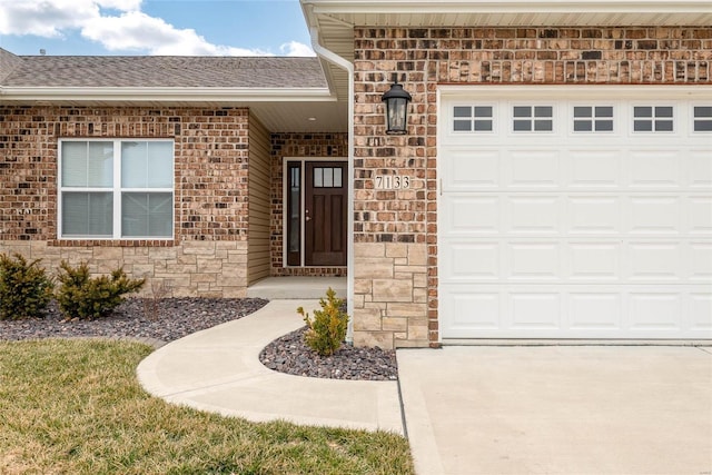 doorway to property featuring a garage and brick siding