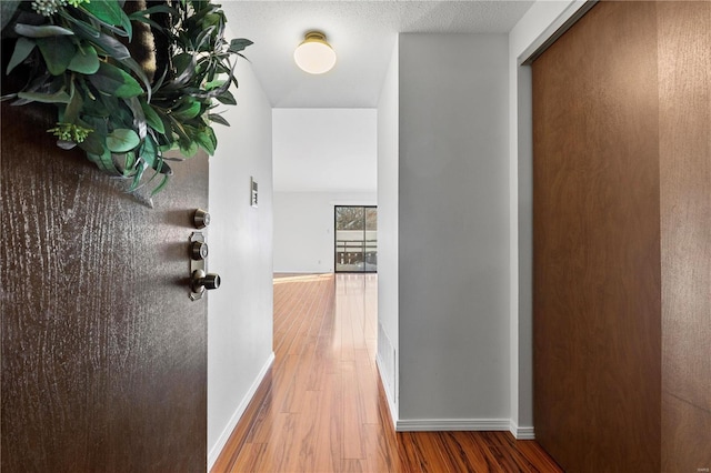 corridor featuring a textured ceiling and wood-type flooring