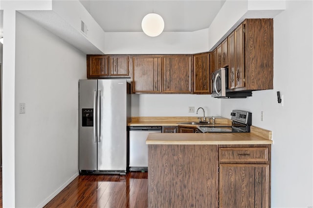 kitchen featuring sink, dark wood-type flooring, kitchen peninsula, and appliances with stainless steel finishes