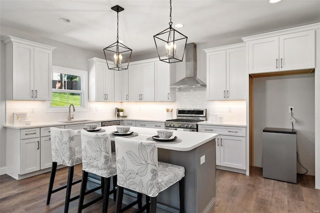 kitchen with stainless steel appliances, white cabinets, and wall chimney range hood