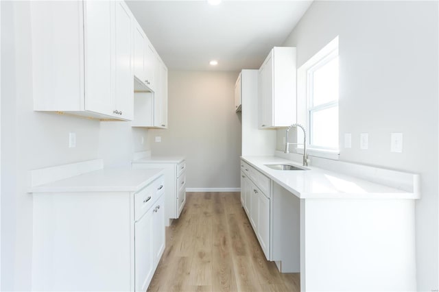 kitchen featuring white cabinets, light hardwood / wood-style floors, and sink