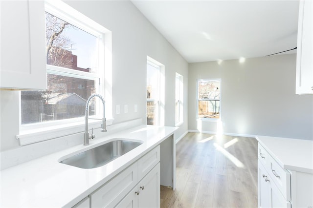 kitchen featuring white cabinets, light wood-type flooring, and sink