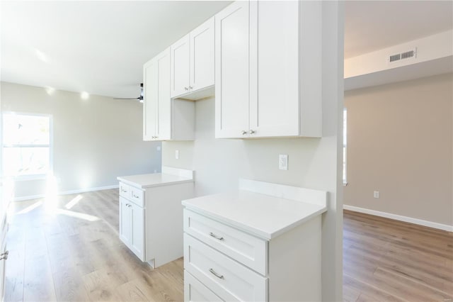 kitchen with white cabinets, ceiling fan, and light hardwood / wood-style flooring