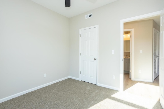 unfurnished bedroom featuring light carpet, sink, and ceiling fan