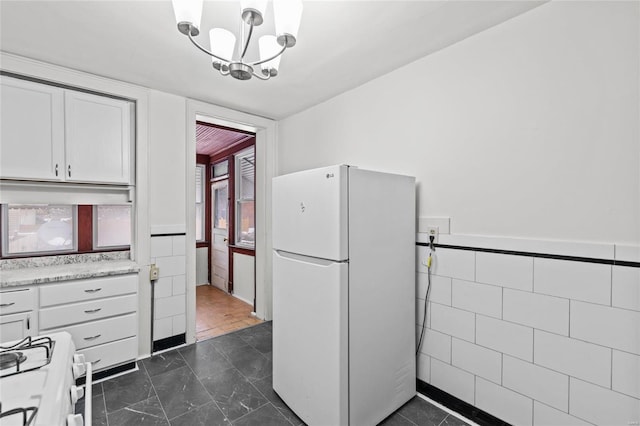 kitchen with white cabinets, white appliances, hanging light fixtures, and tile walls