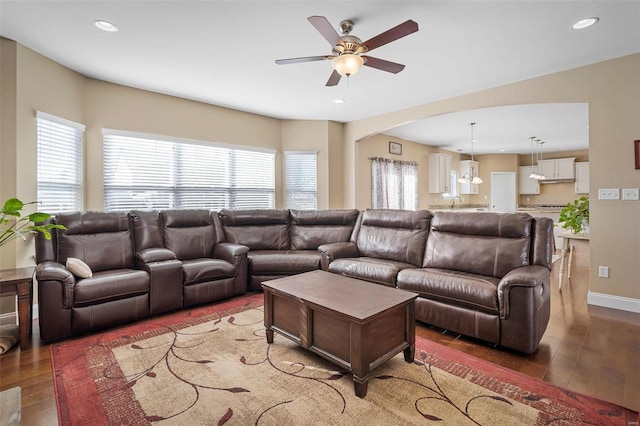 living room featuring dark wood-type flooring, ceiling fan, and a wealth of natural light