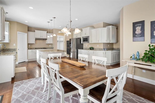 dining area with sink, dark wood-type flooring, and a chandelier