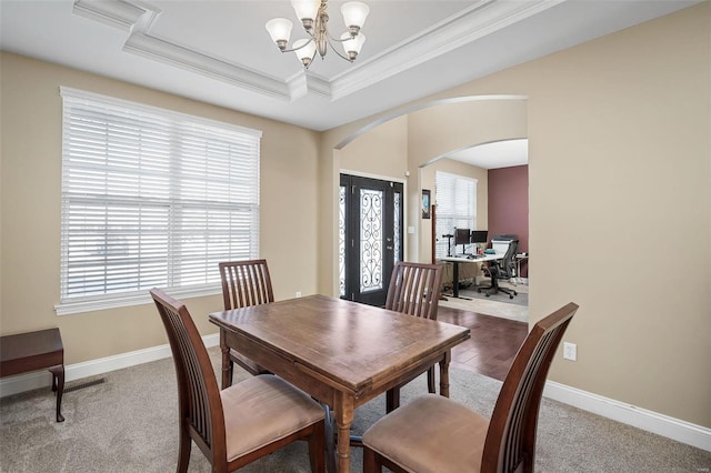 dining room featuring crown molding, carpet flooring, a raised ceiling, and an inviting chandelier