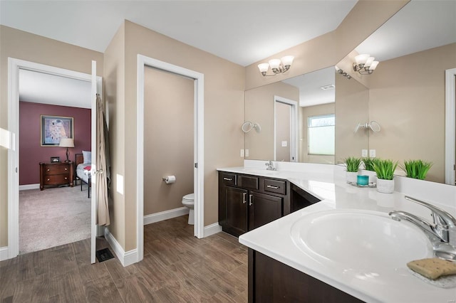 bathroom featuring vanity, hardwood / wood-style flooring, toilet, and an inviting chandelier