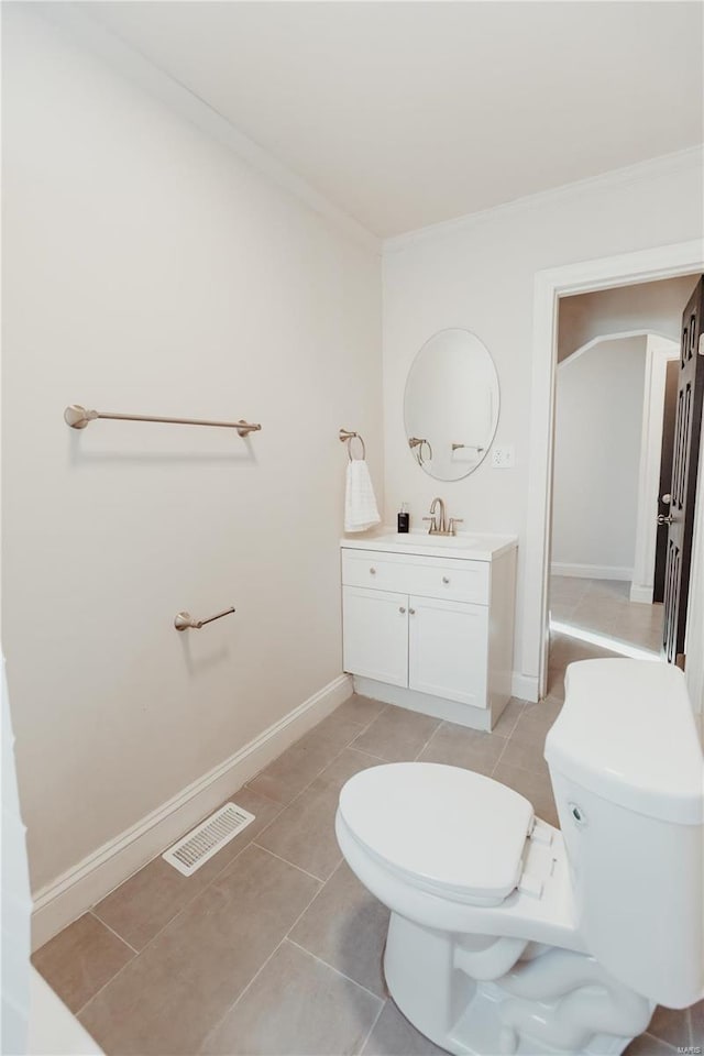 bathroom featuring tile patterned flooring, vanity, ornamental molding, and toilet