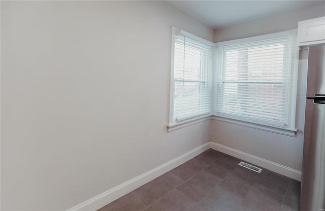 unfurnished room featuring a healthy amount of sunlight and dark tile patterned floors