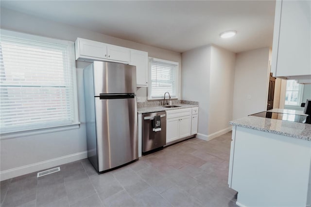 kitchen with white cabinetry, sink, stainless steel appliances, and light stone counters