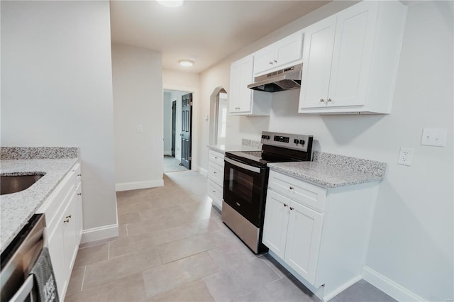 kitchen featuring light tile patterned flooring, appliances with stainless steel finishes, white cabinetry, and light stone counters