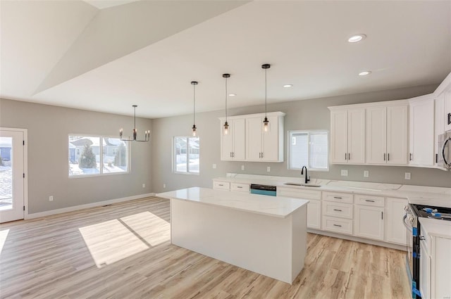 kitchen with sink, stainless steel appliances, a kitchen island, decorative light fixtures, and white cabinets