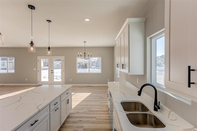 kitchen featuring light stone countertops, sink, white cabinets, and french doors