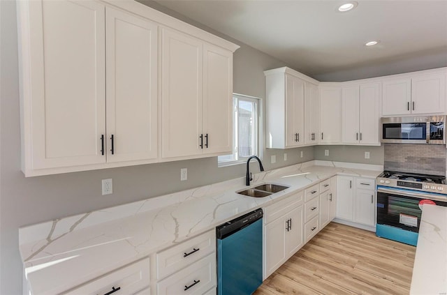 kitchen featuring sink, decorative backsplash, light stone countertops, appliances with stainless steel finishes, and white cabinetry