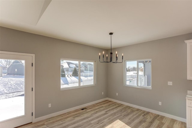 unfurnished dining area with light hardwood / wood-style flooring and a chandelier