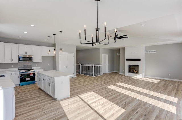 kitchen with a fireplace, a center island, white cabinets, and stainless steel appliances