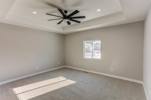 spare room with a tray ceiling, ceiling fan, and light colored carpet