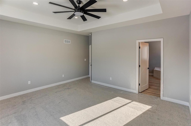 unfurnished bedroom with ceiling fan and a tray ceiling