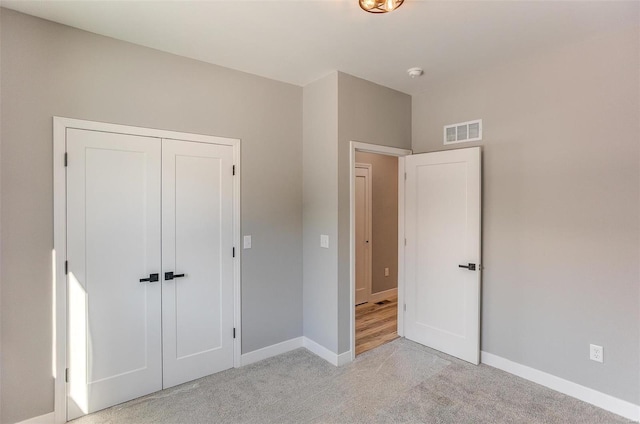 unfurnished bedroom with light colored carpet and a closet