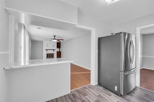 kitchen featuring ceiling fan, kitchen peninsula, stainless steel fridge, and light hardwood / wood-style flooring