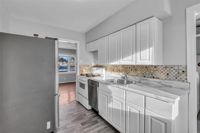 kitchen with tasteful backsplash, sink, light hardwood / wood-style flooring, stainless steel appliances, and white cabinets