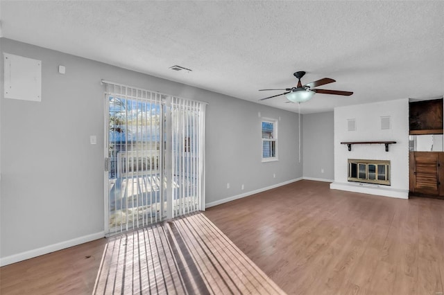 unfurnished living room featuring ceiling fan, wood-type flooring, and a textured ceiling