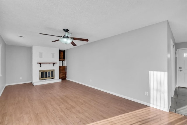 unfurnished living room with ceiling fan, a textured ceiling, and light hardwood / wood-style flooring