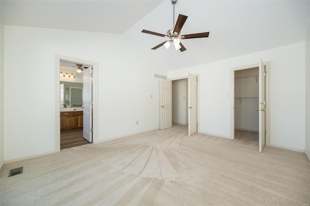 unfurnished bedroom with ensuite bathroom, a closet, lofted ceiling, a walk in closet, and ceiling fan