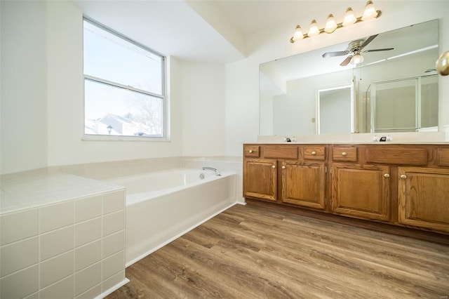 bathroom featuring hardwood / wood-style flooring, ceiling fan, a bath, and vanity