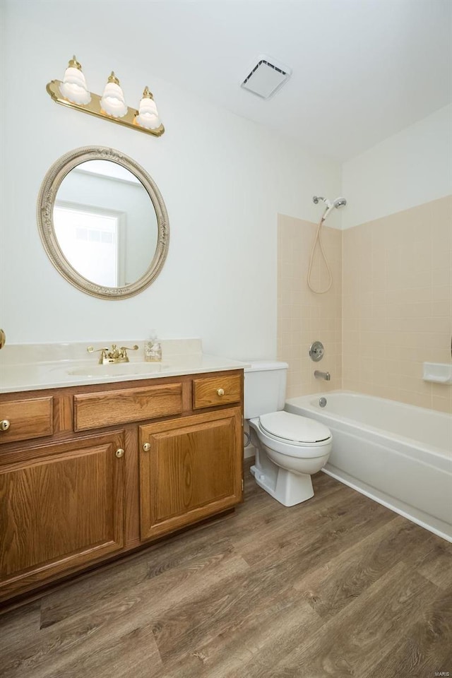 full bathroom featuring tiled shower / bath, toilet, vanity, and wood-type flooring