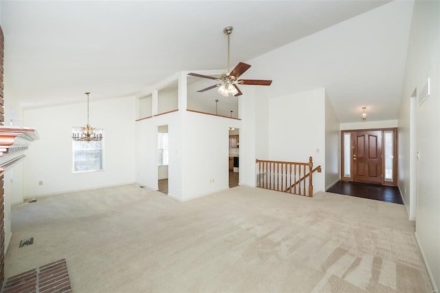 unfurnished living room with ceiling fan with notable chandelier, a brick fireplace, high vaulted ceiling, and carpet flooring