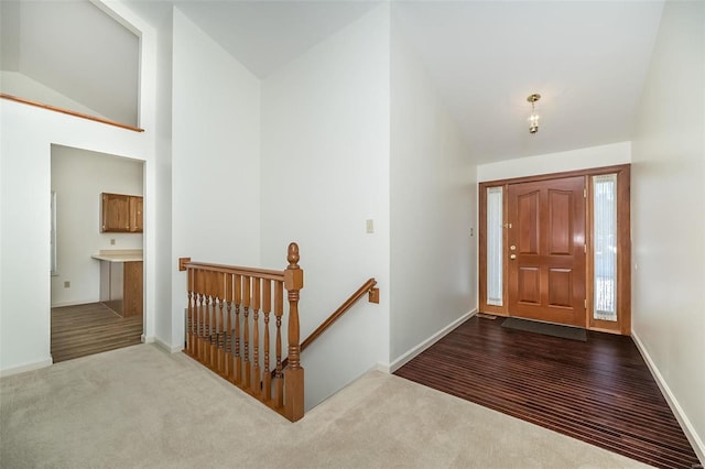 entrance foyer featuring vaulted ceiling and carpet