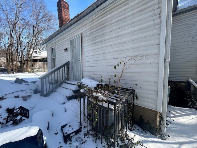 snow covered property entrance with cooling unit