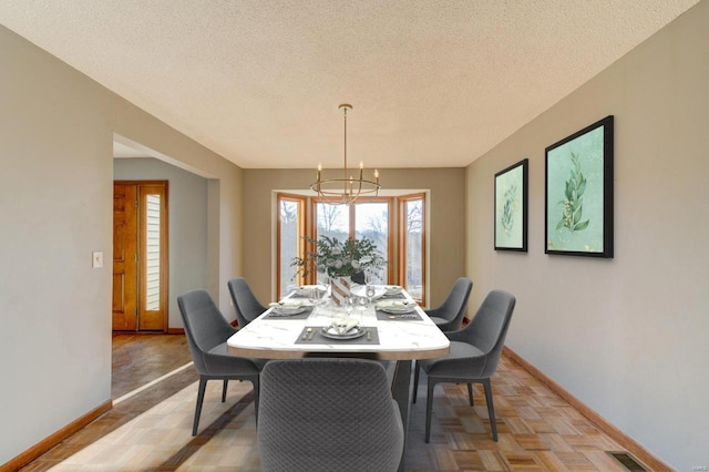 dining area featuring a textured ceiling, light parquet flooring, and an inviting chandelier