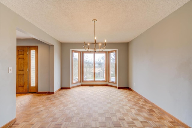 unfurnished dining area featuring light parquet floors, a textured ceiling, and a chandelier