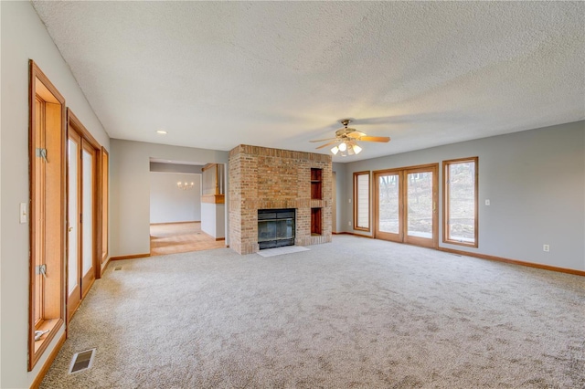 unfurnished living room featuring a textured ceiling, ceiling fan, light colored carpet, and a fireplace