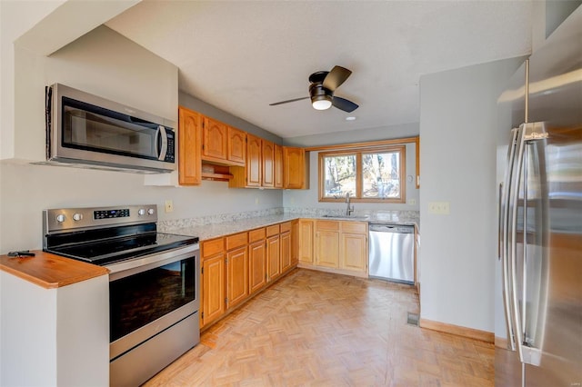 kitchen featuring ceiling fan, sink, light parquet flooring, and stainless steel appliances