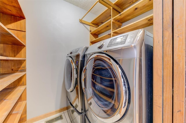 clothes washing area featuring tile patterned flooring, independent washer and dryer, and a textured ceiling