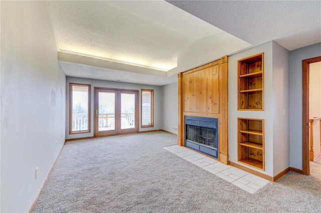 unfurnished living room featuring light carpet, built in features, and a textured ceiling